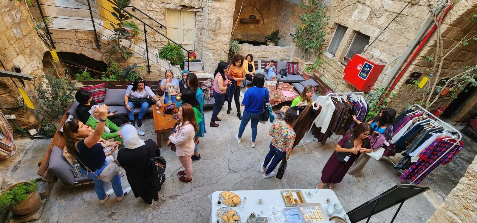 מבט מלמעלה על חצר אבן עם מתלי בגדים, פינות ישיבה ומבקרות