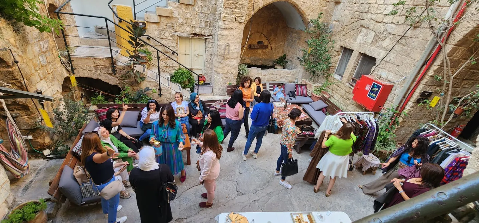 מבט מלמעלה על חצר אבן מלאה מבקרות, לצד מתלי בגדים