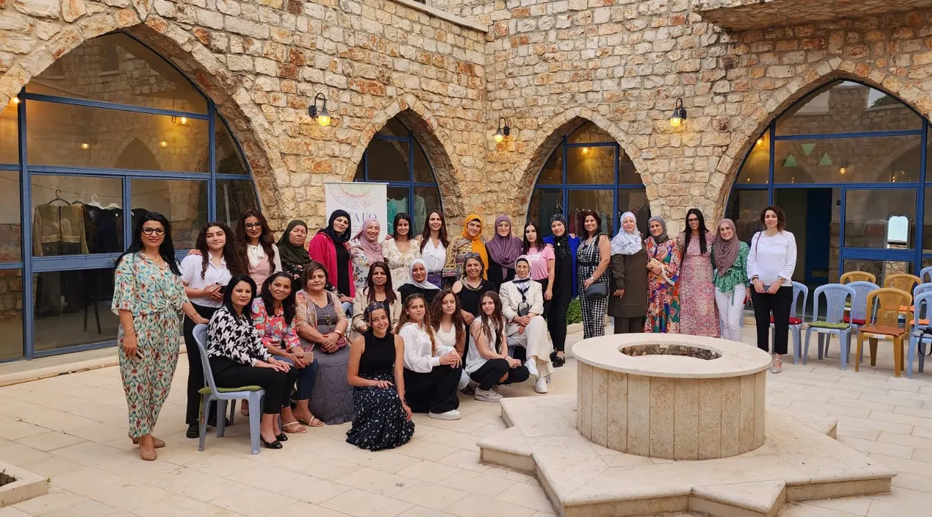קבוצת נשים מצטלמת סביב באר אבן בחצר עם קשתות