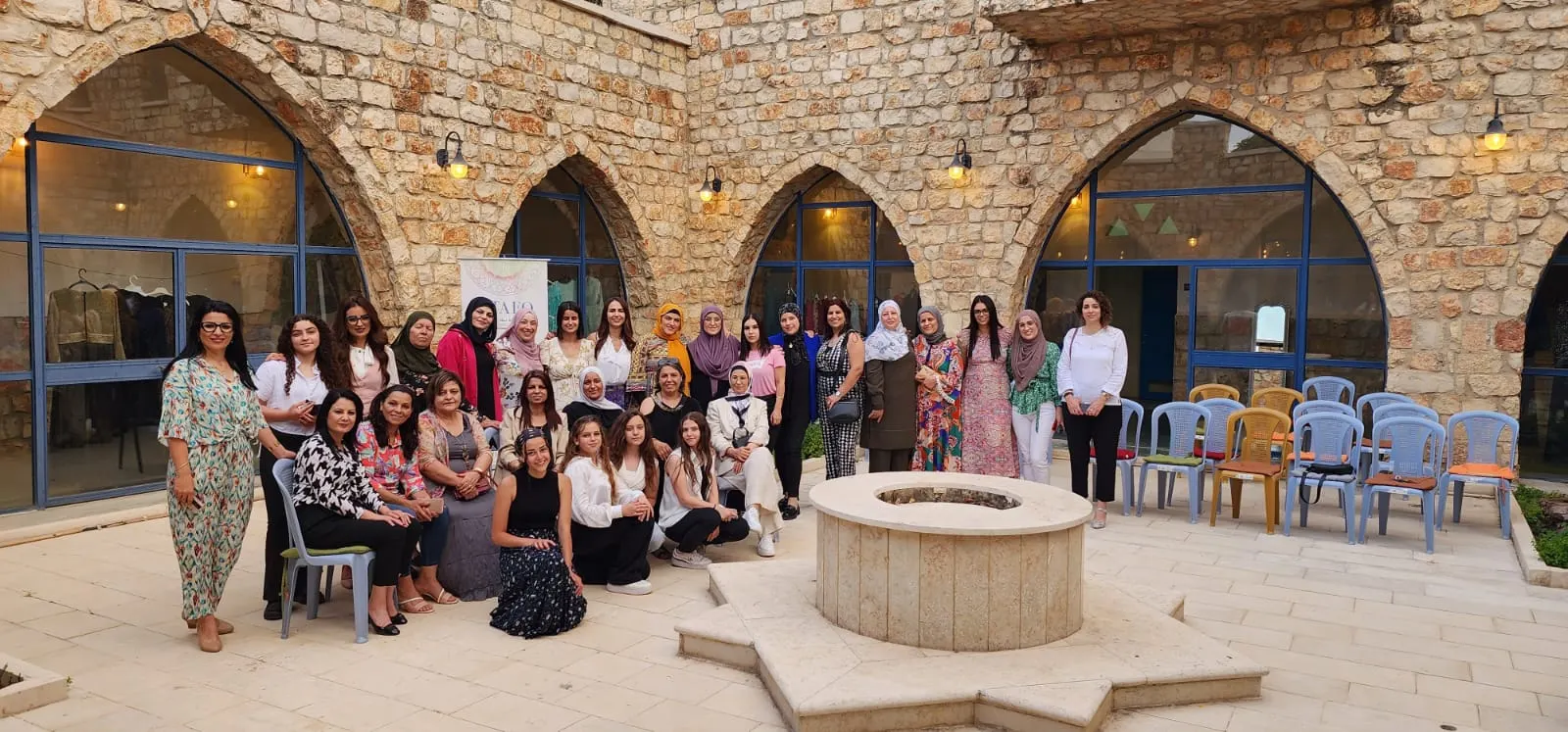 קבוצה גדולה של נשים מצטלמת בחצר אבן עם קשתות